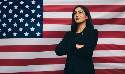 Pensive congresswoman standing against an American flag