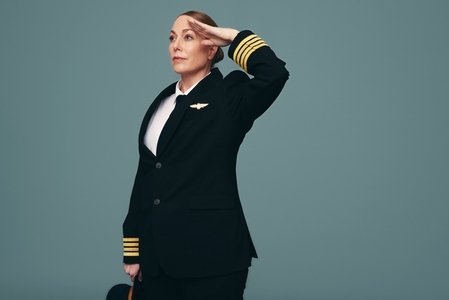 Professional pilot saluting while standing in a studio