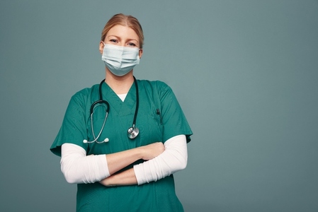 Female doctor wearing a face mask and green scrubs