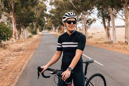 Fit woman wearing sportswear and cycling helmet taking a rest from practicing on empty road