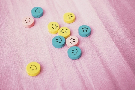 Smiley faces in pastel tones against a pink background