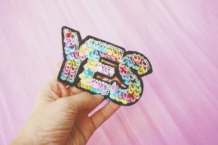 Word yes make with colorful sequins against pink background