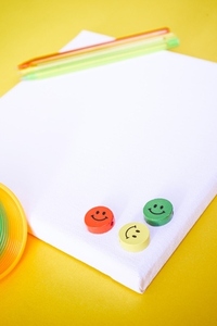 Close up of three colorful smiley faces over a white canvas