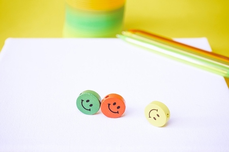 Close up of three colorful smiley faces over a white canvas