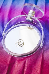 Two silver weading rings over a mirror against a rainbow backgro