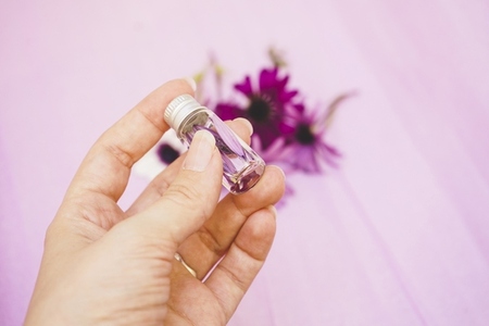 Close up of a hand holding an aromatherapy bottle filled with wa