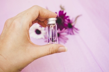 Close up of a hand holding an aromatherapy bottle filled with wa
