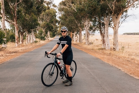 Athlete taking a break from cycling on an empty country road
