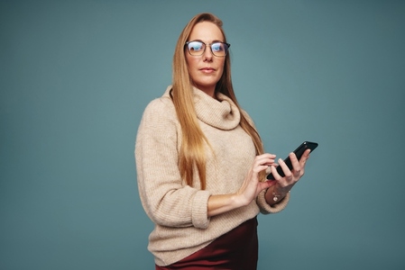 Confident woman using a smartphone in a studio