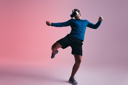 Sporty young man kicking a virtual ball in the metaverse