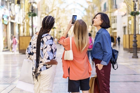 Multiracial ladies taking self portrait on cellphone on street