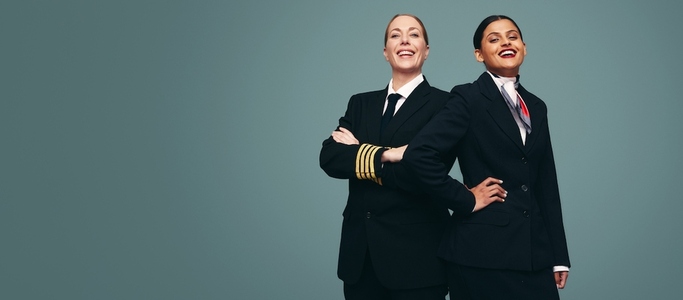 Airline captain and air hostess smiling happily in a studio
