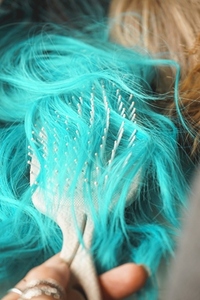 Close up of a brush brushing a colored wig