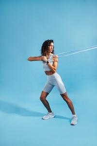Woman doing intense core strength training using resistance band on blue background
