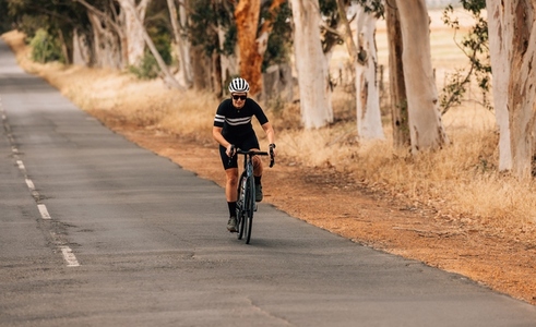 Athletic woman taking a intense bicycle ride on the empty countryside road
