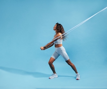 Female working out with elastic band on blue background  Slim athletic woman working on core strength with resistance band