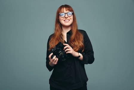 Cheerful young photographer smiling at the camera in a studio