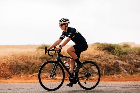 Side view of professional woman cyclist riding her bike outdoors