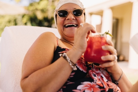 Happy senior woman enjoying a cocktail while on vacation