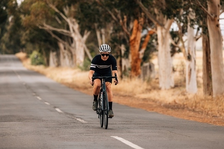 Professional cyclist in sportswear practicing on a long countryside road