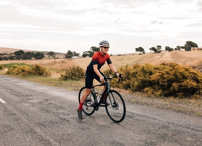 Professional woman cyclist starting to ride on empty countryside road
