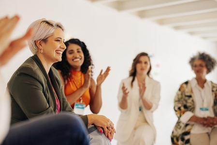 Smiling businesswomen applauding their colleague in an office