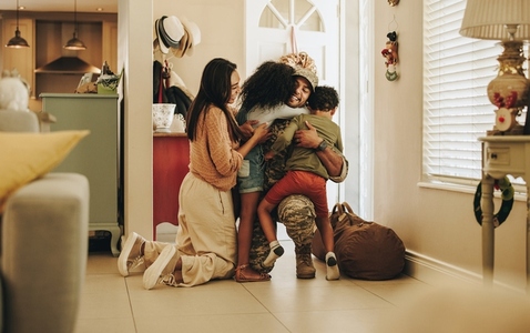 Happy army soldier reuniting with his family at home