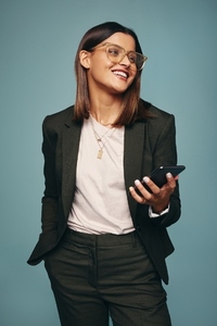 Happy young woman holding a mobile phone in a studio