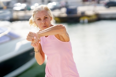 Elderly female doing shadow boxing outdoors  Senior woman doing sport in a coastal port