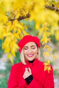 Delighted elegant lady smiling and enjoying autumn nature with closed eyes