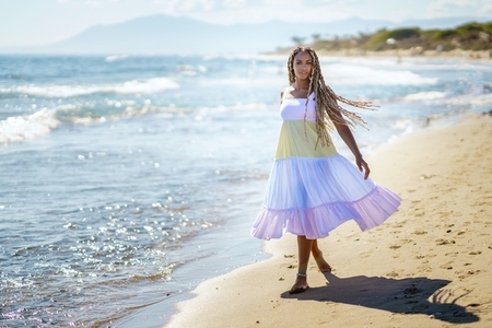 Black woman walking on beach near sea