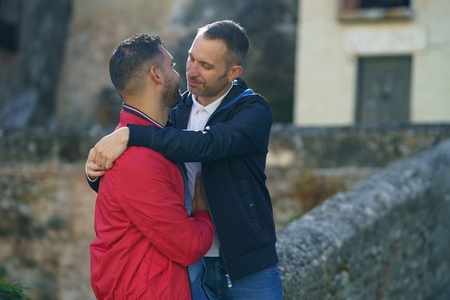 Couple of gay men embracing in city