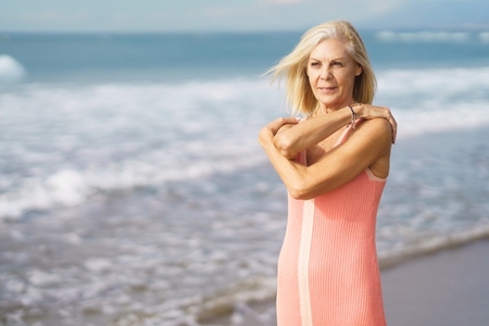 Mature woman enjoying her free time looking at the sea from the shore of the beach