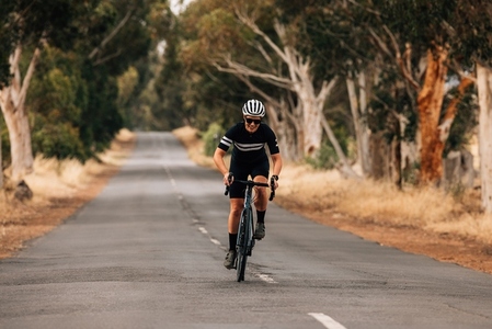 Young woman in sportswear on road bike doing intense training on empty countryside road
