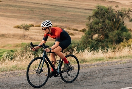 Woman riding a bicycle on empty road  Sportswoman in fitnesswear practicing on pro bike