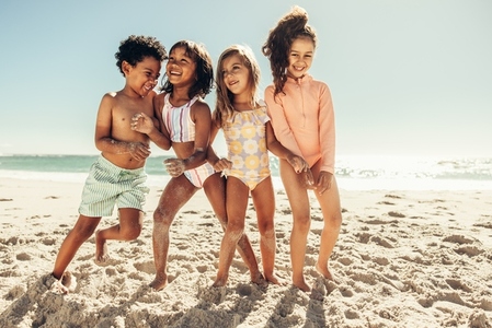 Multiethnic kids playing together on beach sand