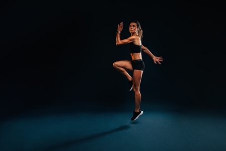 Female athlete jumping and stretching  Healthy woman exercising in studio warming up