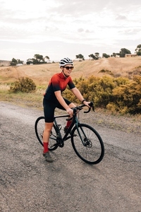 Woman cyclist in helmet and sunglasses relaxing during ride on countryside  Professional road bike rider in sports wear