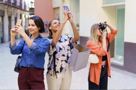 Positive diverse women taking photos of city