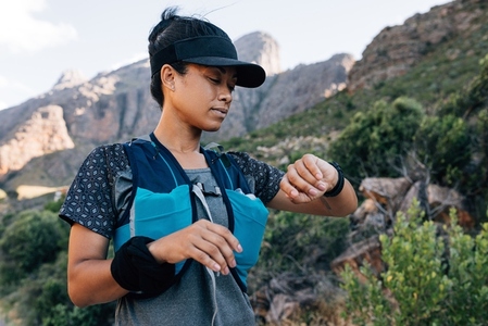 Woman hiker looking at smart watch  Female in sportswear checking a distance on fitness tracker