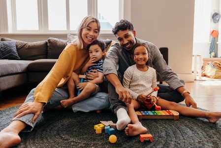 Young family smiling happily in their living room at home