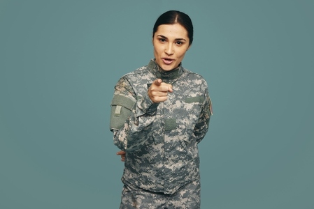 Young military servicewoman pointing at the camera in a studio