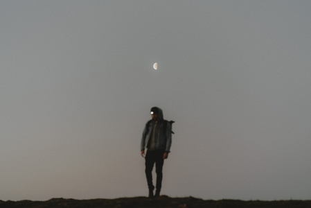 Half moon over blurred man hiking