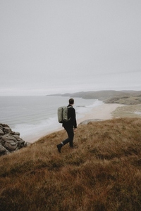 Man hiking on hill overlooking tranquil ocean beach