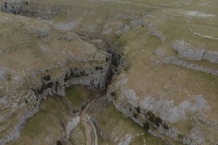 Aerial view stream through rugged cliffs in remote landscape