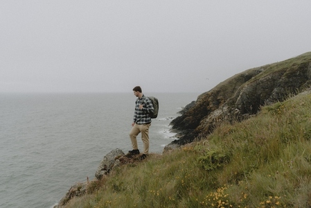 Male hiker on rugged cliff above ocean