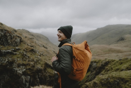 Portrait happy male hiker with backpack in rugged landscape