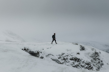 Man hiking on snowy mountain rocks