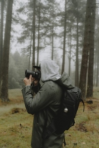 Male photographer with SLR camera in rainy woods
