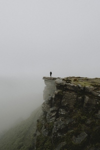 Male hiker at the edge of rocky hilltop in rainy 2